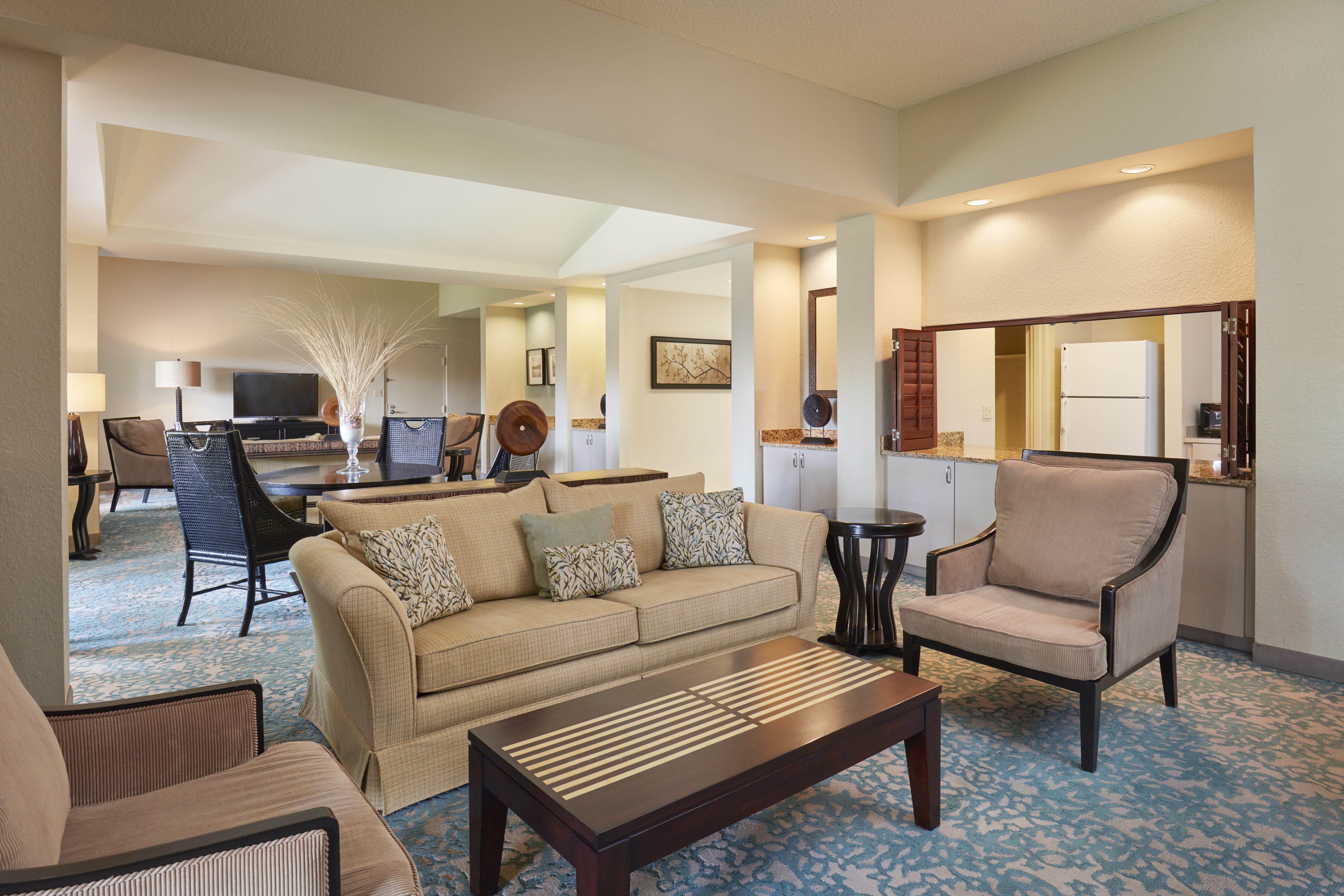 Sala de estar de la suite con sillas de lounge, televisor y cocina