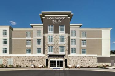Welcoming Homewood Suites hotel exterior featuring fresh landscaping and bright blue sky.