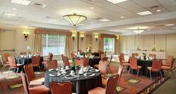 Round Dining Tables With Place Settings and Flowers on Black Linens in Ballroom Set Up for Business Reception