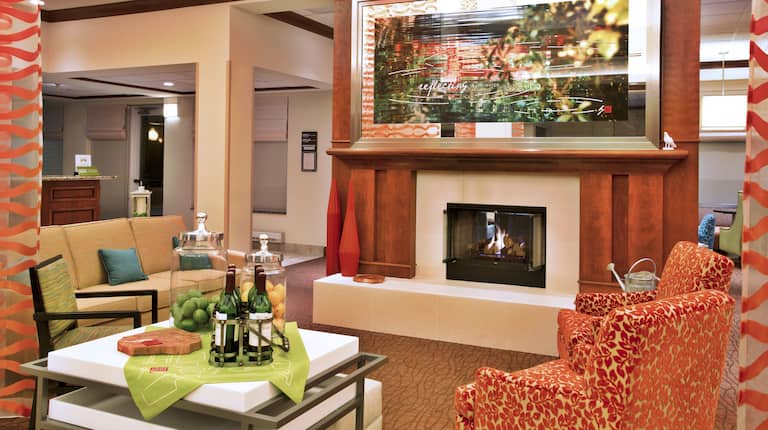 Beverage Station, Long Drapes, and Soft Seating Around Fireplace in Lobby Lounge Area With Art Feature