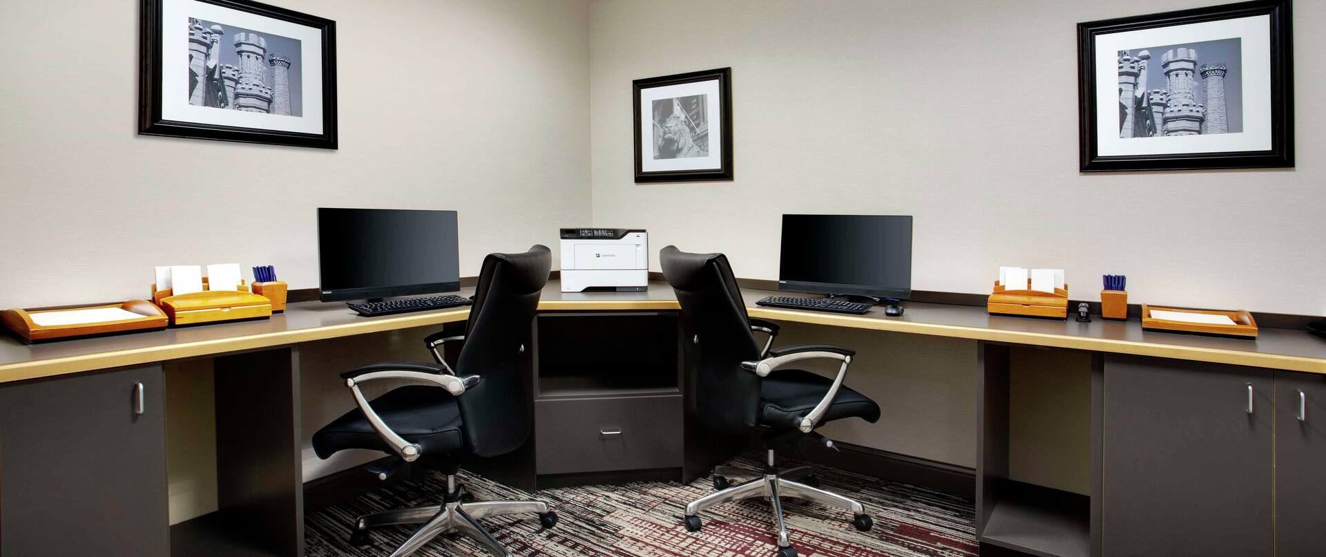 a corner desk with two computers and chairs