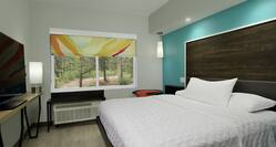 One King Bed Guest Room with Bright Blue Accent Wall behind Large Wooden Headboard 