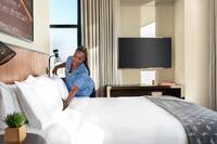 A housekeeping team member making a bed in a hotel room