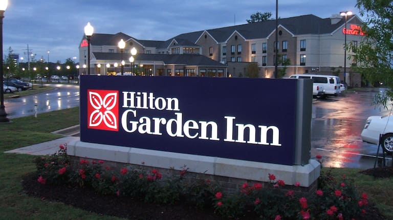 Illuminated Signage and Hotel Exterior at Night and Guest Cars on Parking Lot
