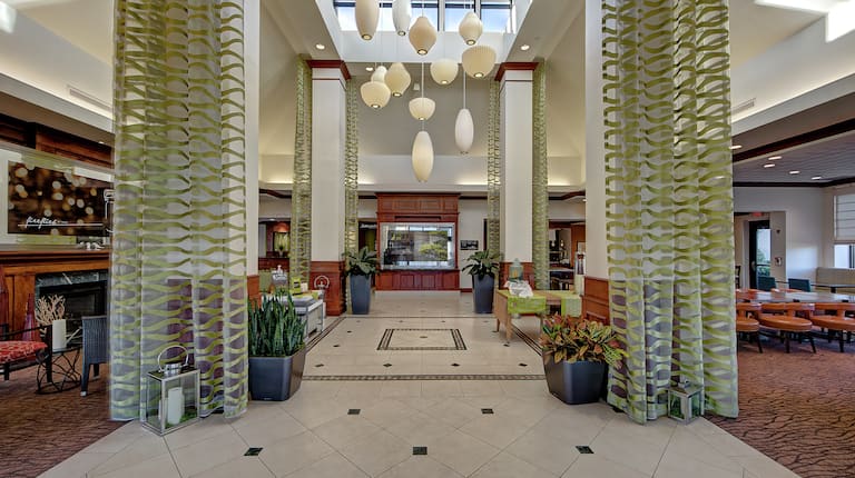 Overview of Lobby With Fireplace, Long Drapes, Decorative Lighting, and View of Dining Area