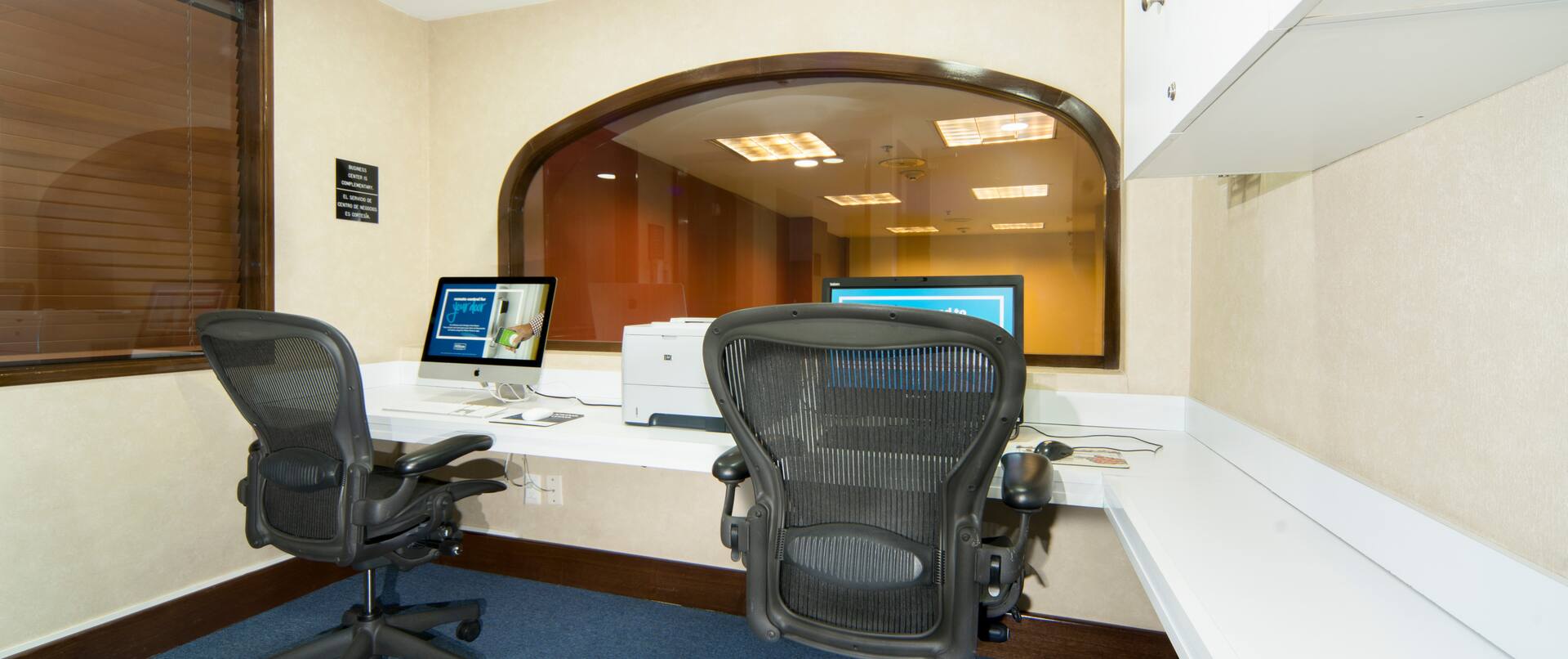 Centro de negocios con dos computadoras, dos sillas de oficina e impresora