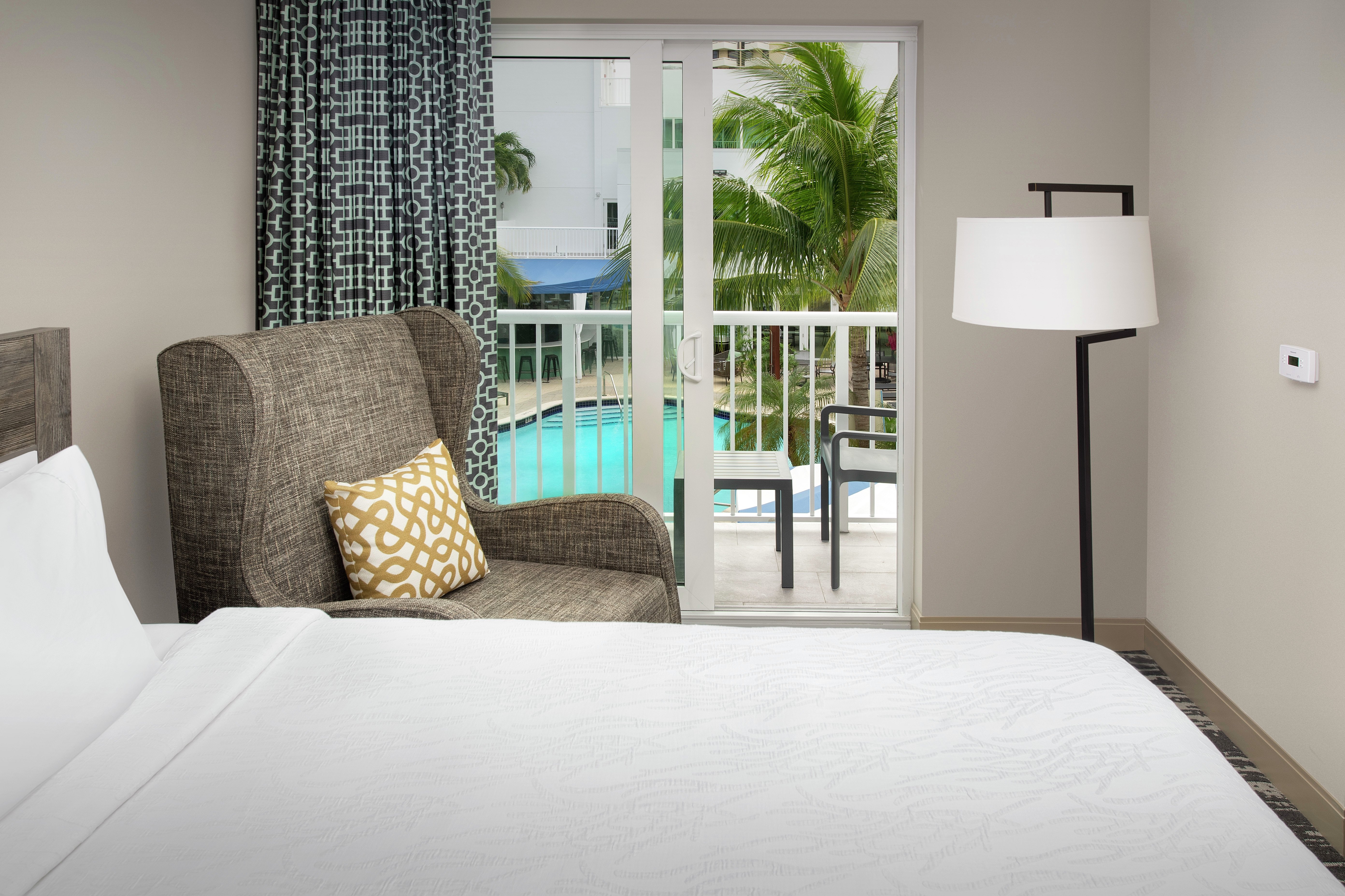 Guestroom with Bed, Lounge Area, and Outside View of Pool