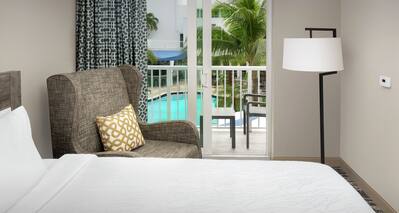 Guestroom with Bed, Lounge Area, and Outside View of Pool