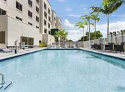 Stunning outdoor pool featuring ample seating, tall palm trees, and accessible chair lift.
