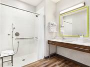 Spacious accessible bathroom featuring convenient roll-in shower with seat and grab bars.