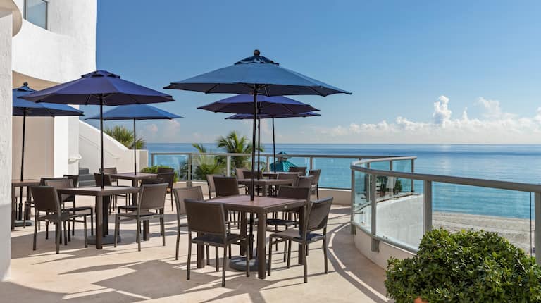 Terraza con mesas, sillas y vista al mar
