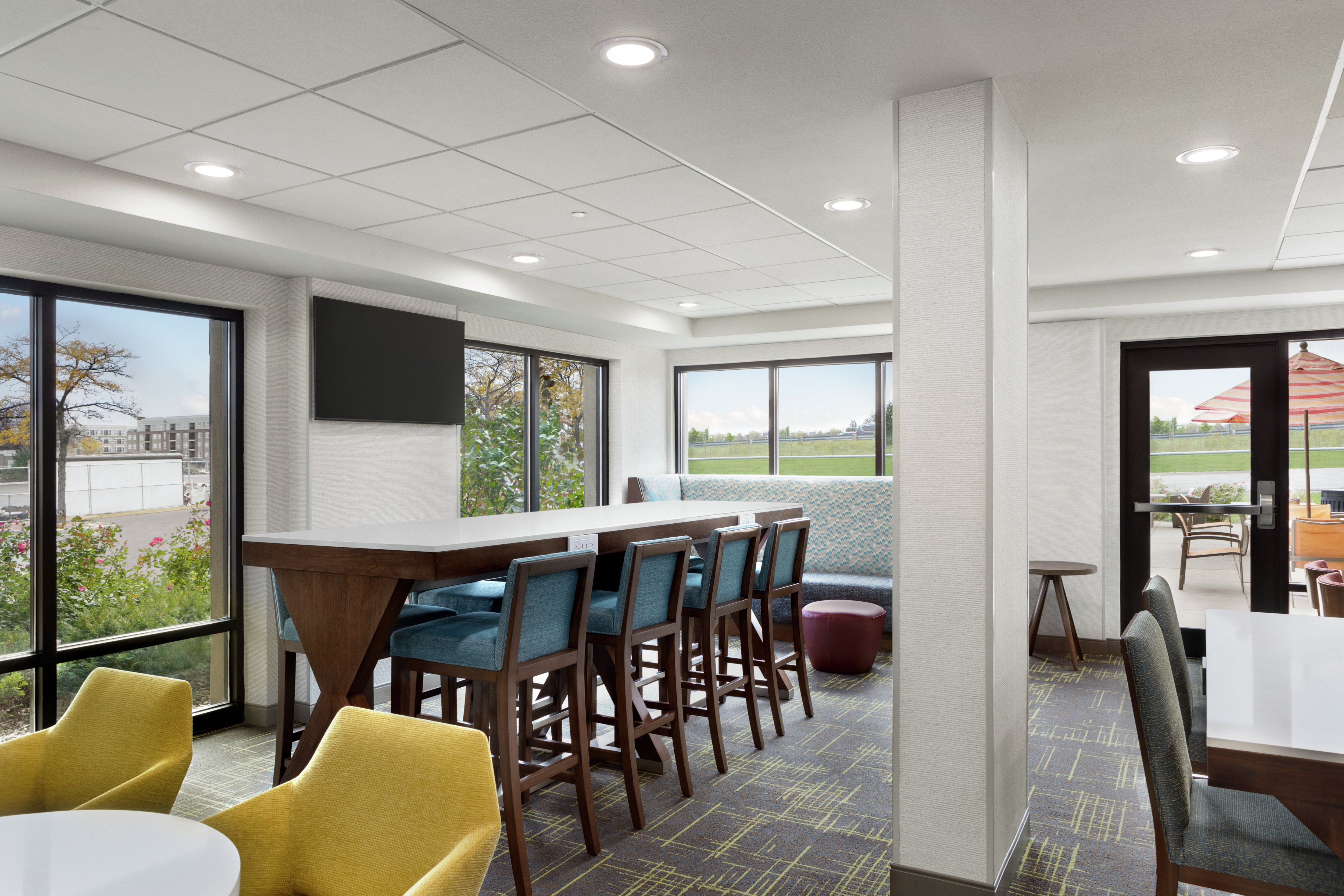 Spacious hotel lobby featuring ample seating, communal table, and large windows with natural light.