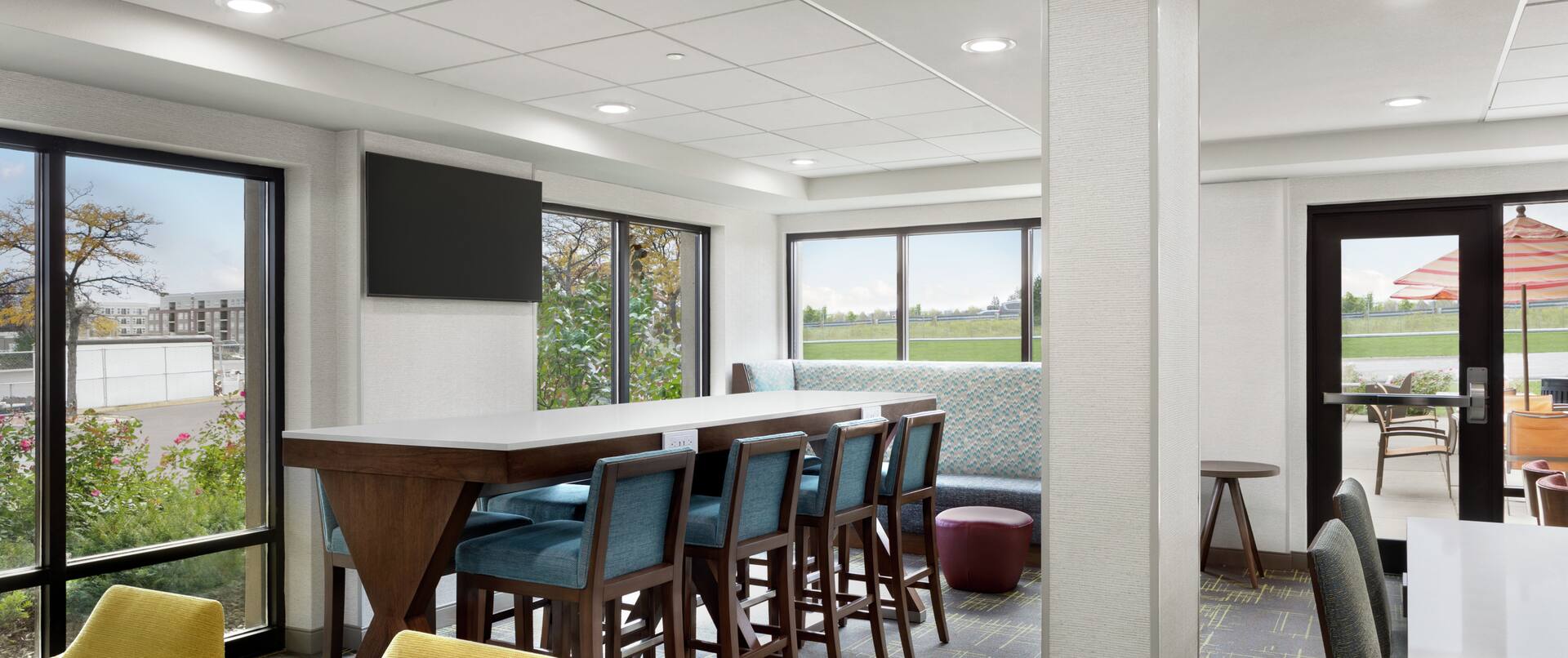 Spacious hotel lobby featuring ample seating, communal table, and large windows with natural light.