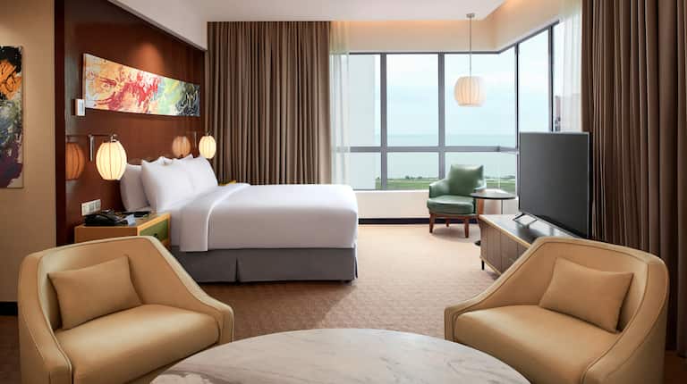 Corner room with panoramic windows, king bed and armchairs and coffee table