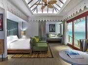 Overwater Villa Bedroom with Bed, Lounge Area, and Outside View