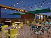 BBQ Grills and Patio Tables, Chairs, and Umbrellas on Outdoor Patio at Dusk