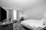 Guest room with one king bed, a TV, and a soft chair and floor lamp near the window.