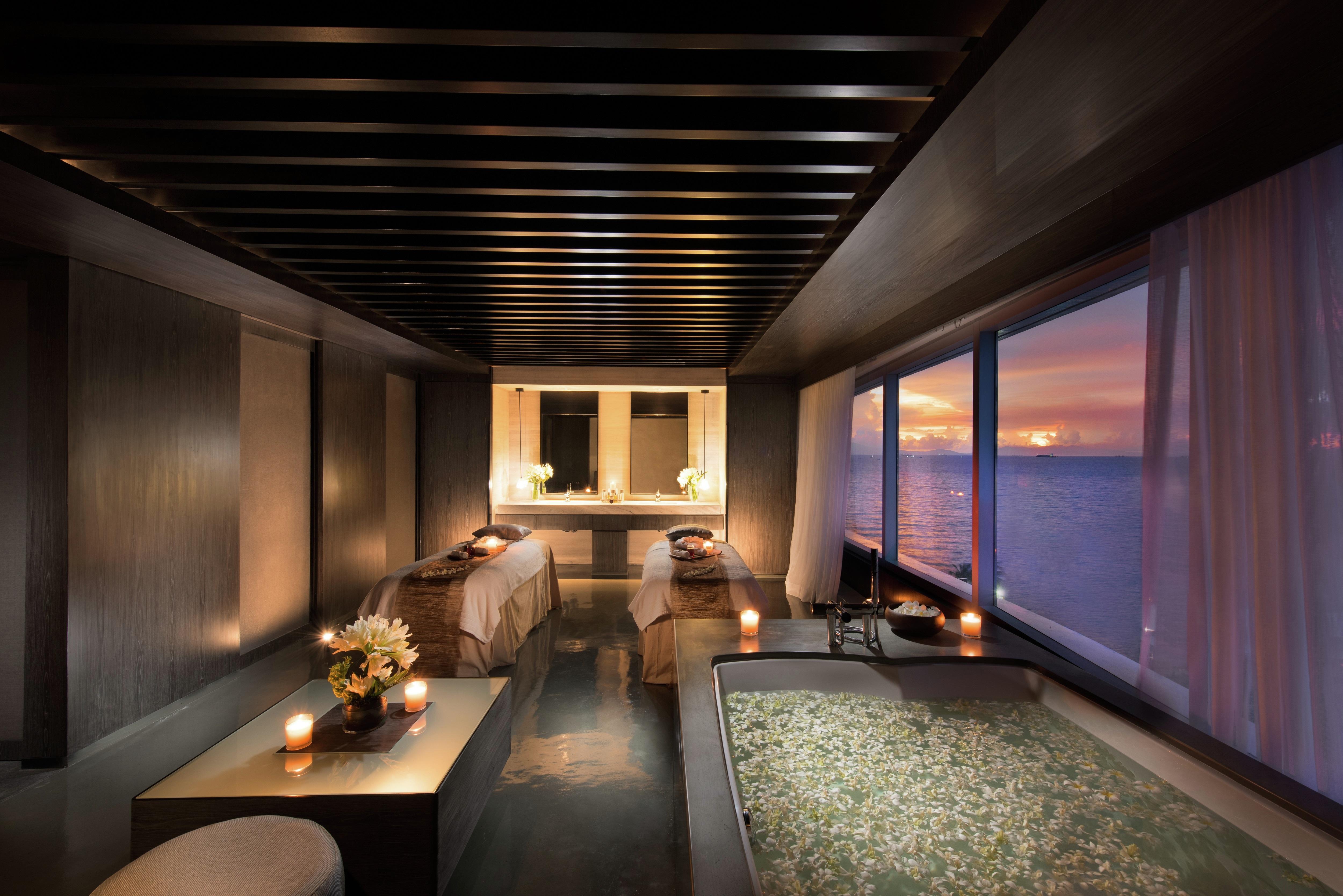 A beautiful spa treatment room with large window overlooking the ocean at sunset.