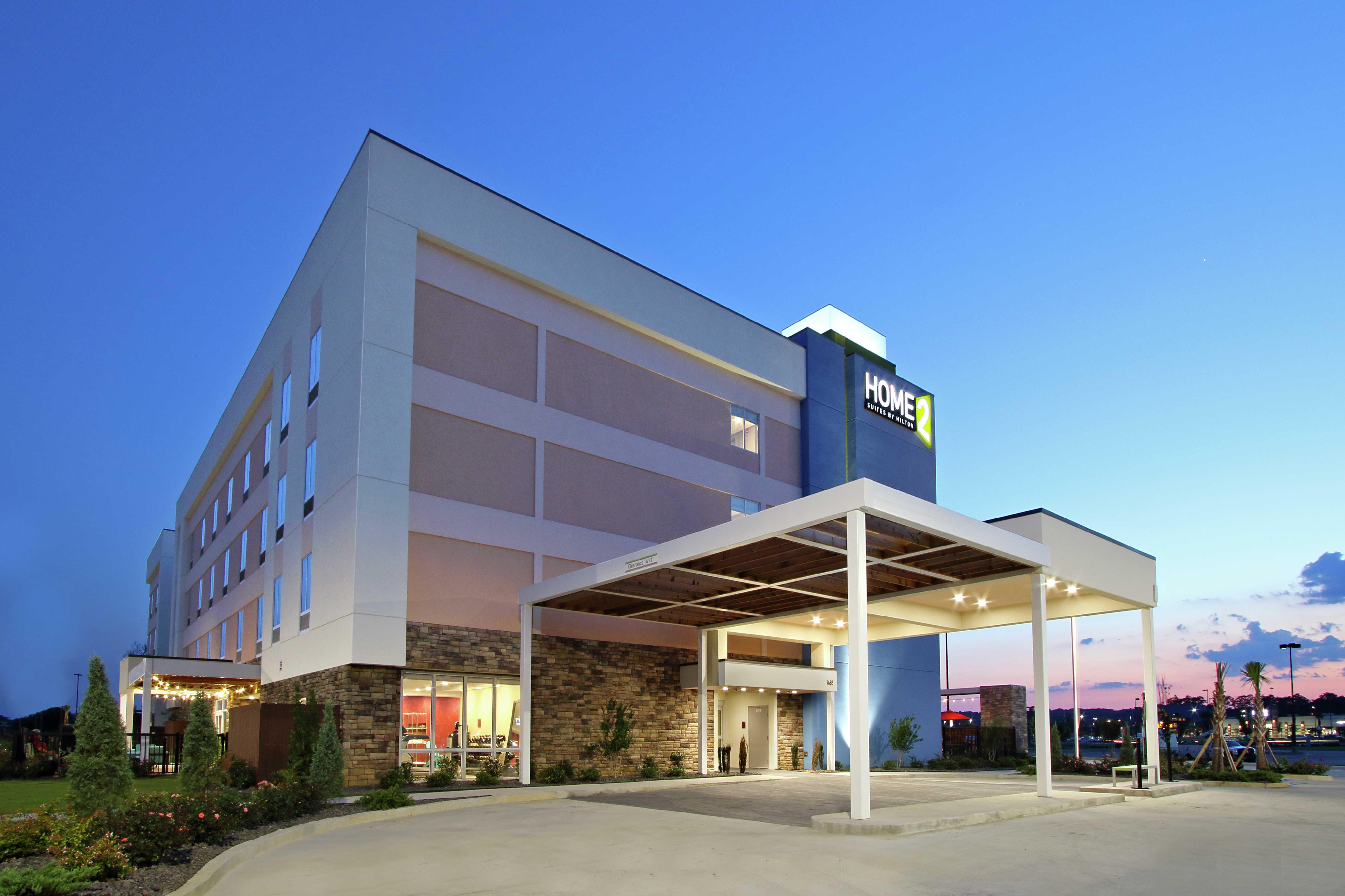 Illuminated Hotel Exterior With Signage, Porte Cochère, and Landscaping at Dusk