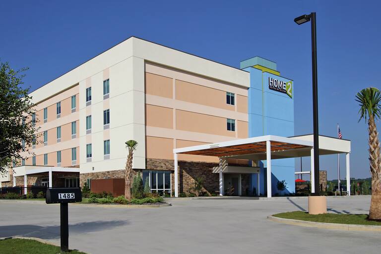 Daytime View of Hotel Exterior With Signage, Porte Cochère, and Landscaping