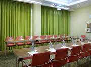 Small Meeting Room With U-Shaped Table, Chairs, and Windows With Long Green Drapes