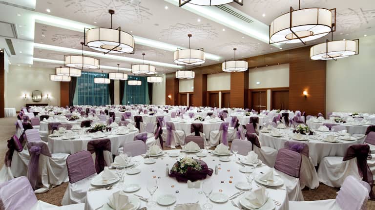 Place Settings and Flowers on Round Tables in Ballroom