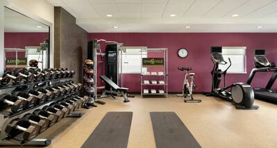 Complimentary on-site fitness center for guests featuring free weights, yoga mats, and cardio machines.