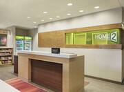 Welcoming Home2 Suites front desk in bright lobby featuring convenient snack shop..
