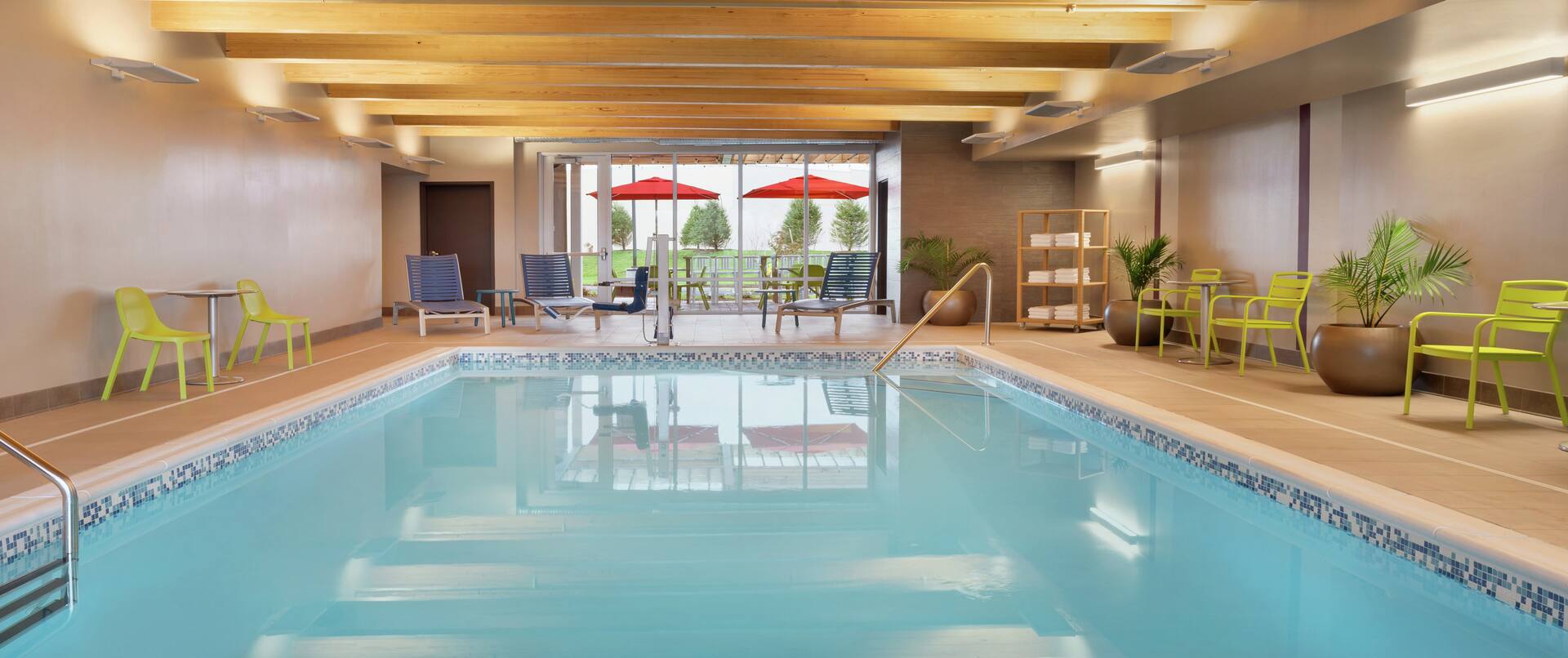 Beautiful indoor pool featuring comfortable seating, large windows, and cedar ceiling.
