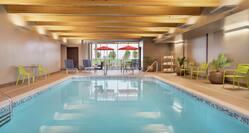 Beautiful indoor pool featuring comfortable seating, large windows, and cedar ceiling.