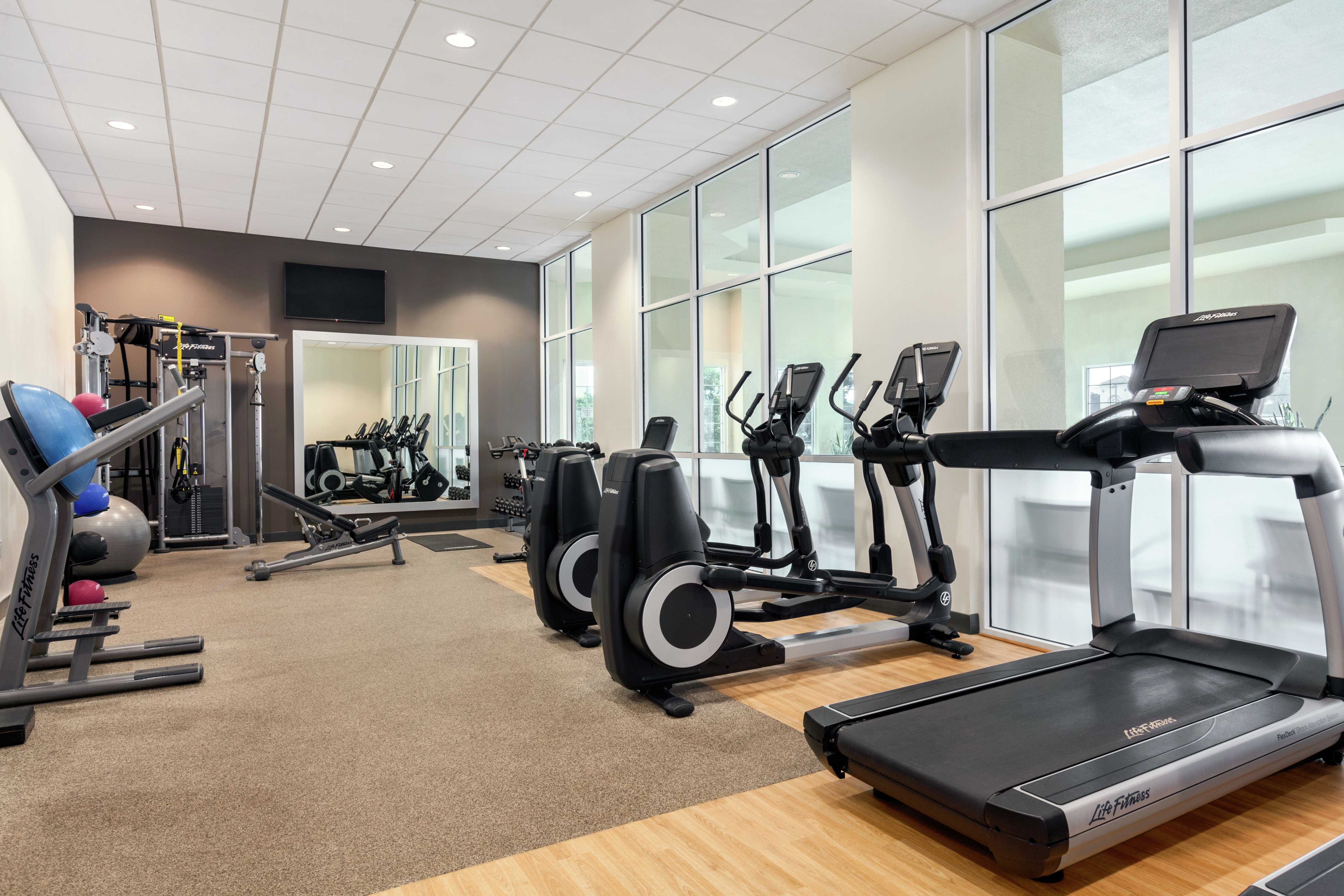 Bright on-site fitness center fully equipped with cardio machines, free weights, and resistance training equipment.