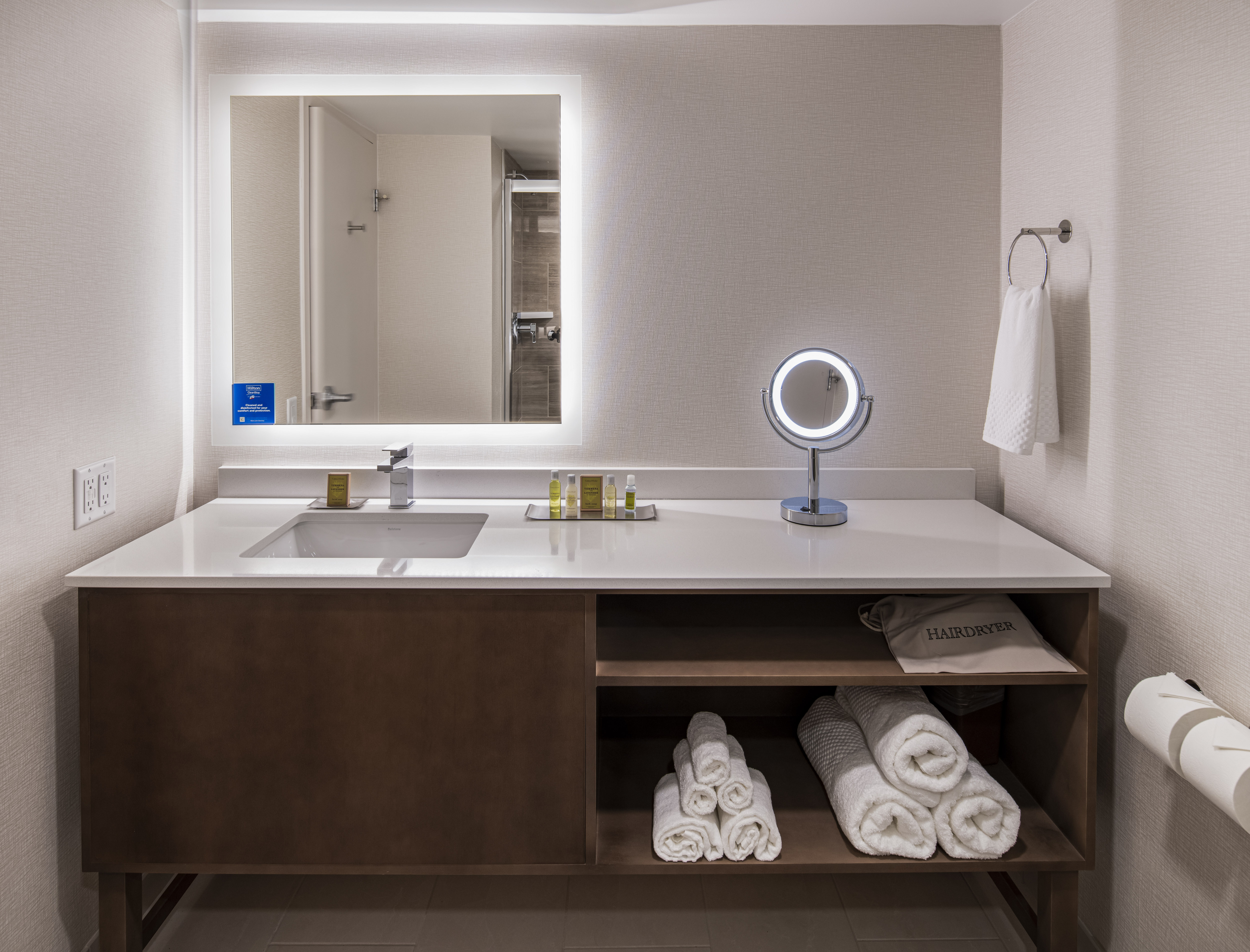 Bathroom Vanity Area with Amenities and Lit Mirror