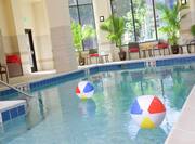 Two Beach Balls in Heated Indoor Pool Surrounded by Windows, Tables, and Chairs 