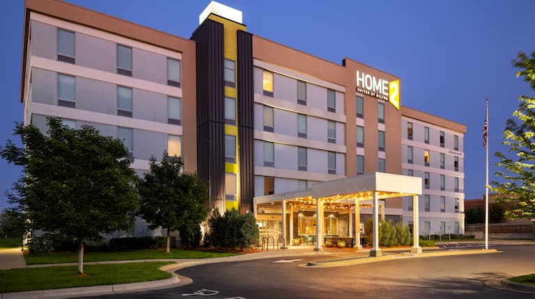 Hotel exterior at dusk, with front entrance and covered drop off area visible.