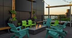 Spacious outdoor rooftop bar featuring firepit and stunning city view.
