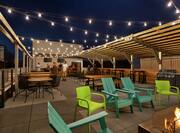 Spacious outdoor rooftop bar featuring ample seating, guests mingling, and grill area.