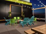 Spacious outdoor rooftop bar featuring firepit, string lights, and stunning city view.