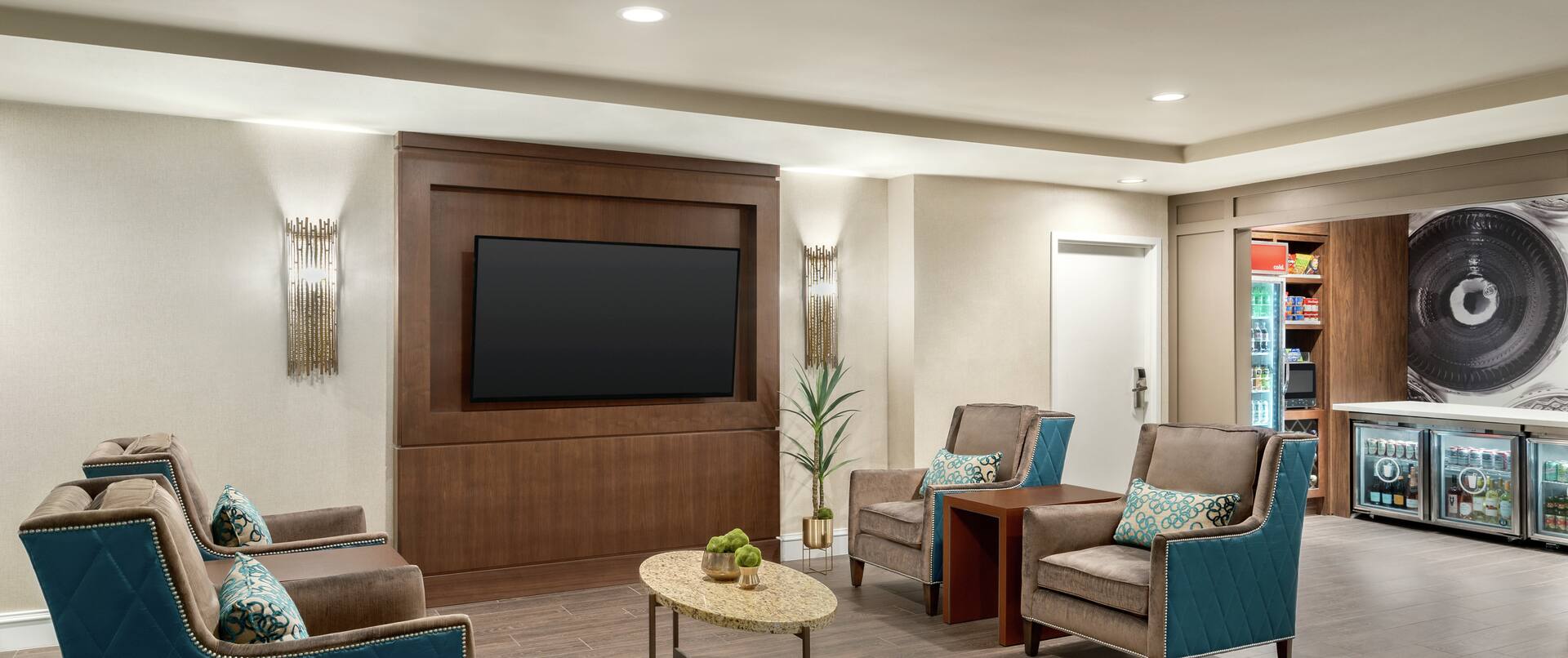 Spacious hotel lobby featuring seating area with TV and convenient on-site market.