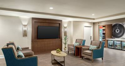 Spacious hotel lobby featuring seating area with TV and convenient on-site market.