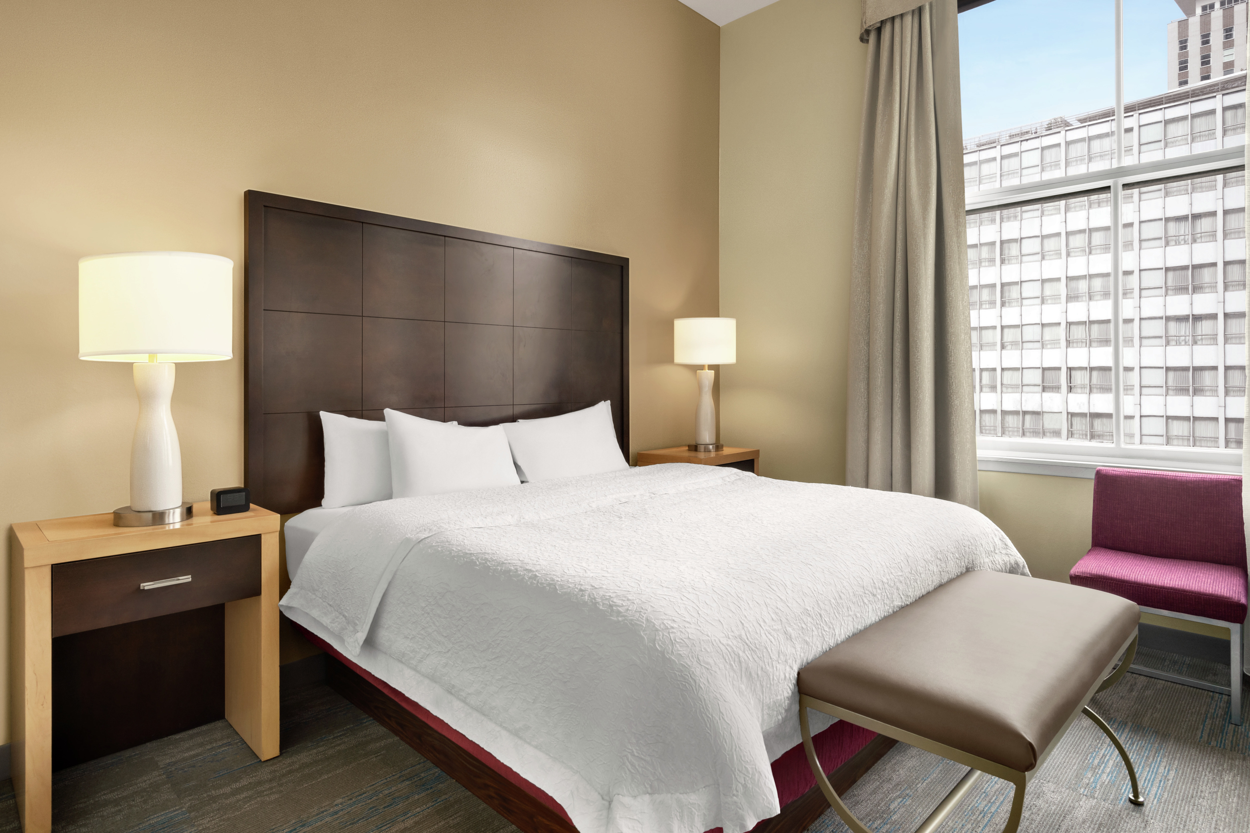 Bright guest bedroom featuring comfortable king bed and beautiful city view.