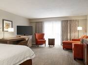 Spacious guest room suite featuring comfortable bed, lounge area with sofa, and work desk.