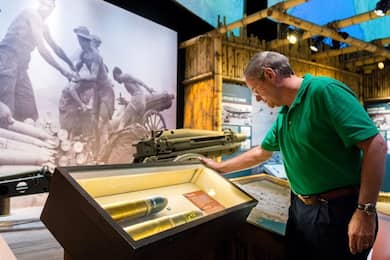Man looking at display case containing artillery shells at the National WWII Museum