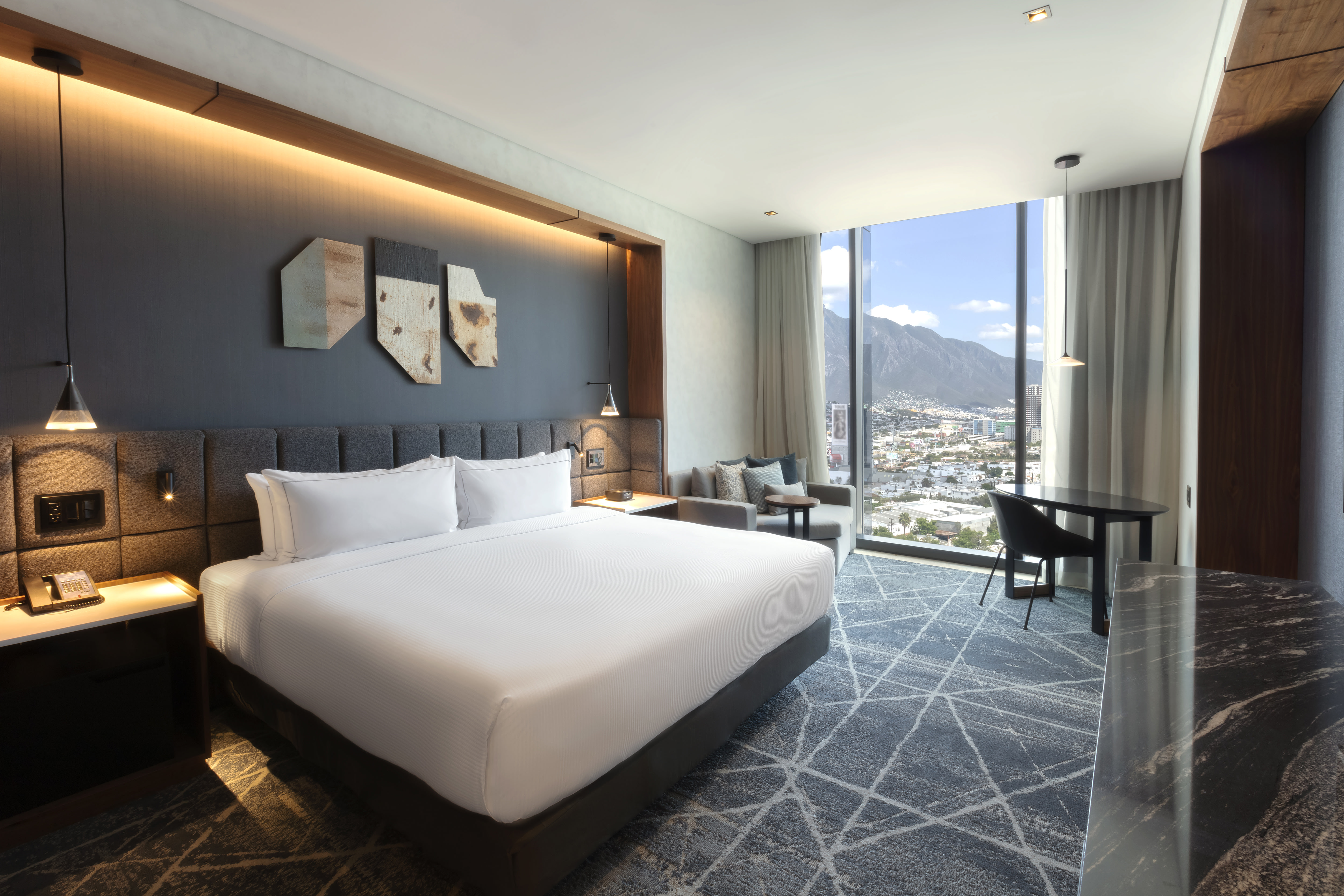 Guest room with king-sized bed and floor-to-ceiling windows with mountain and city views