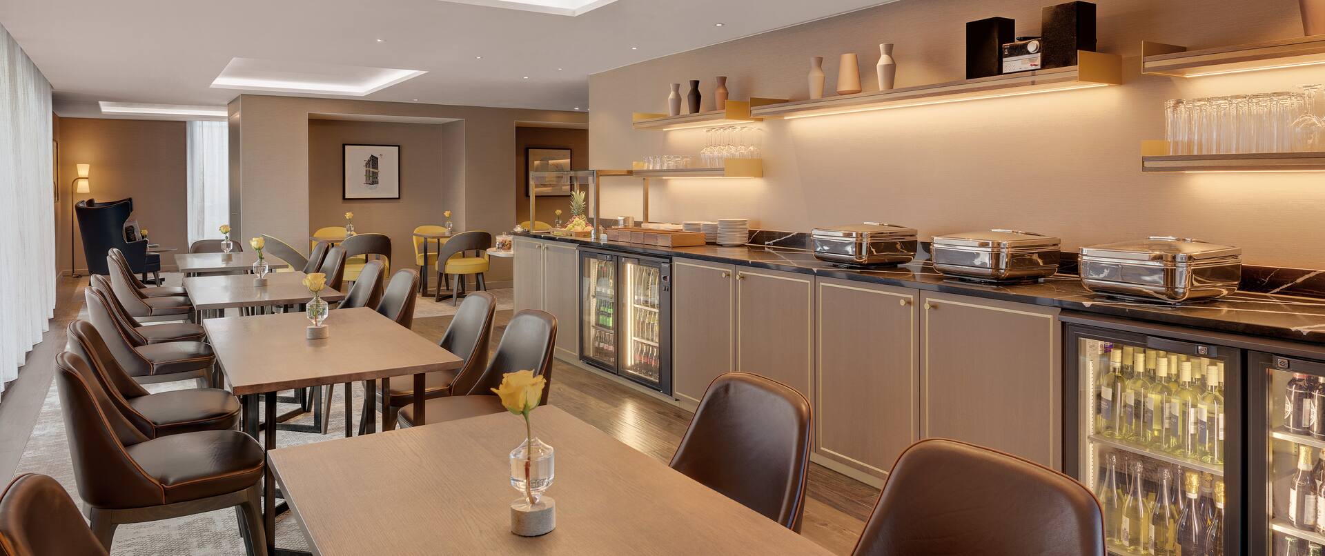 Executive Lounge – Tische gegenüber Buffetbereich und Getränkekühlschrank