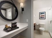 Coffeemaker Area and Partial View of Bathroom with Shower in Hotel Guest Room
