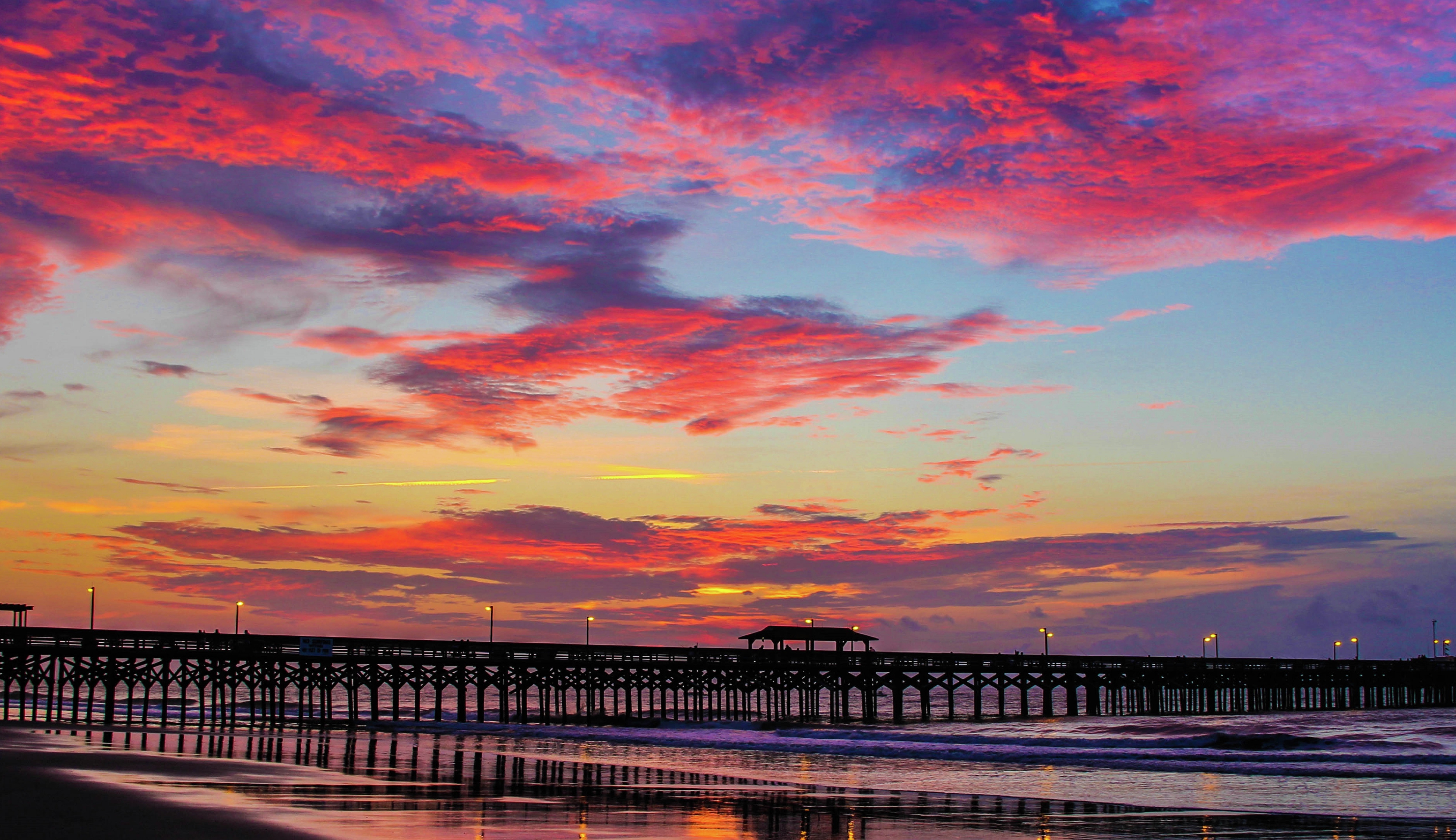 a pier on a beach at sunset