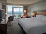 Hotel room with a king bed and wall of windows that includes a sliding door to the balcony with views of the ocean.