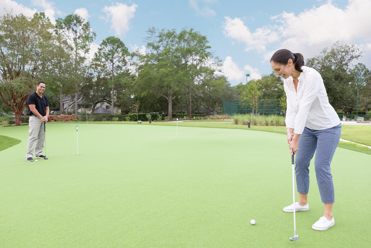 Arka Planda Ayakta Duran Bir Adamla Birlikte Yeşili Putter Üzerinde Tutan Kadın