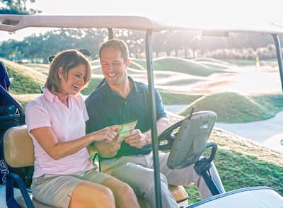 Man and woman on golf cart looking at scorecard