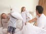 Family having a pillow fight in bedroom